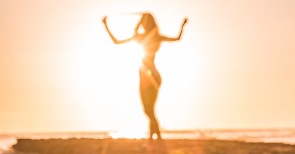 A woman celebrates at sunset on a beach in San Diego, creating a stunning silhouette.