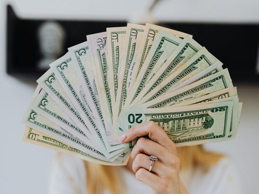 A person holding a fan of US dollar bills, symbolizing wealth and financial success.