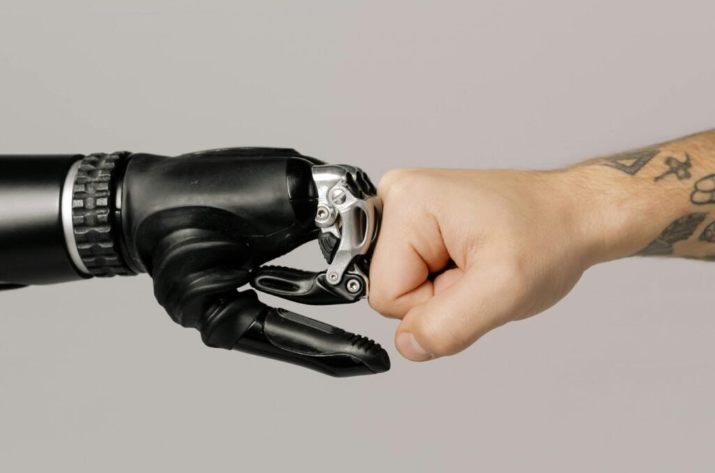 Close-up of a human fist bumping a prosthetic hand, symbolizing technology and human connection.